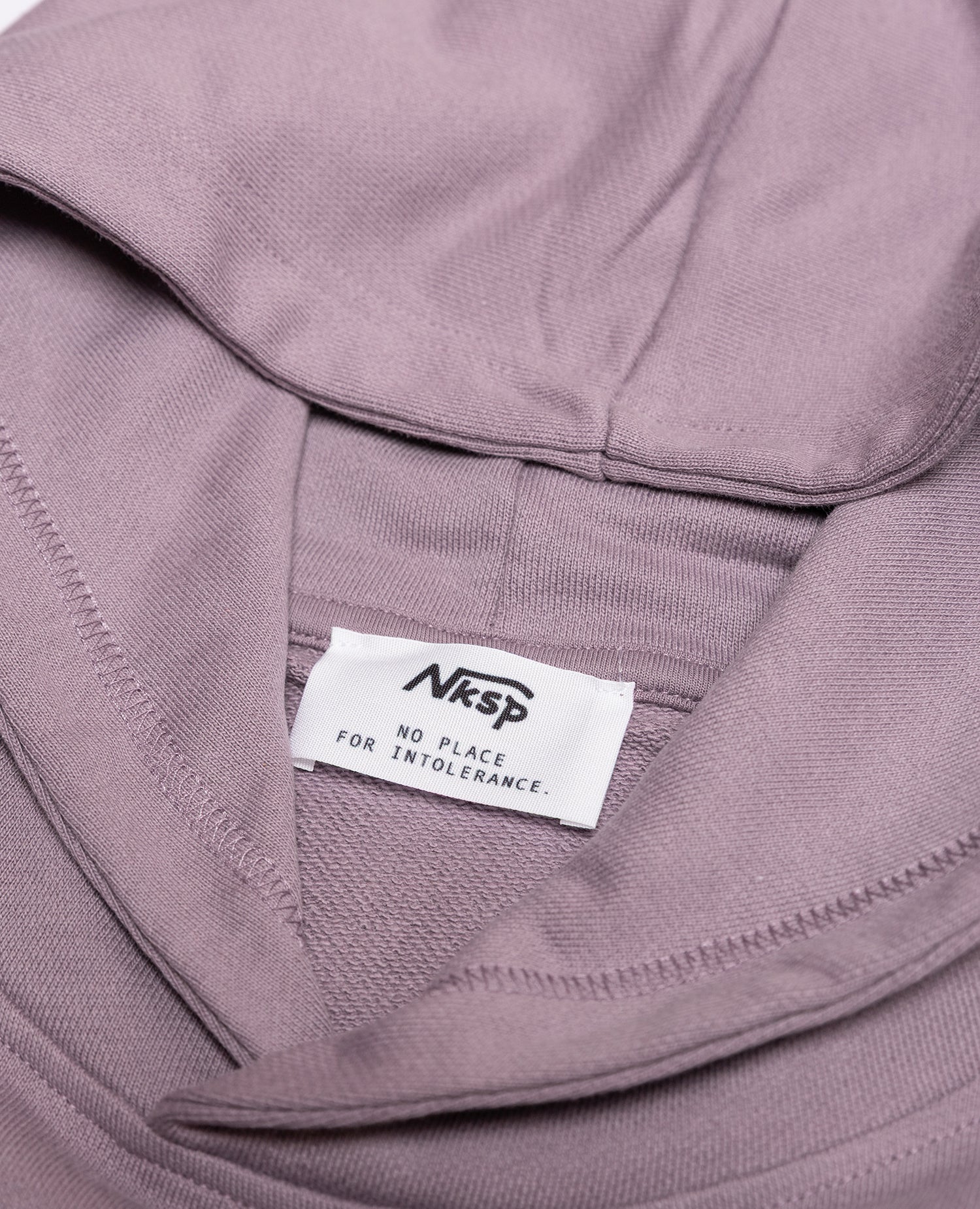 Blume Hoodie Lila von NKSP – Detail mit Nackenlabel „No place for intolerance“