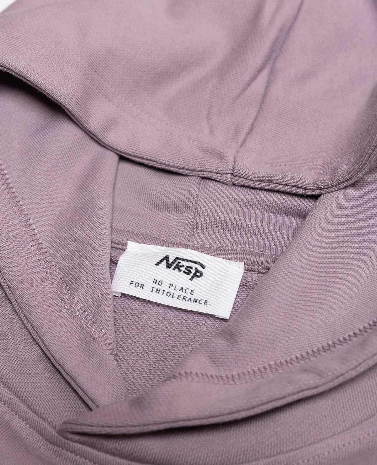 Blume Hoodie Lila von NKSP – Detail mit Nackenlabel „No place for intolerance“